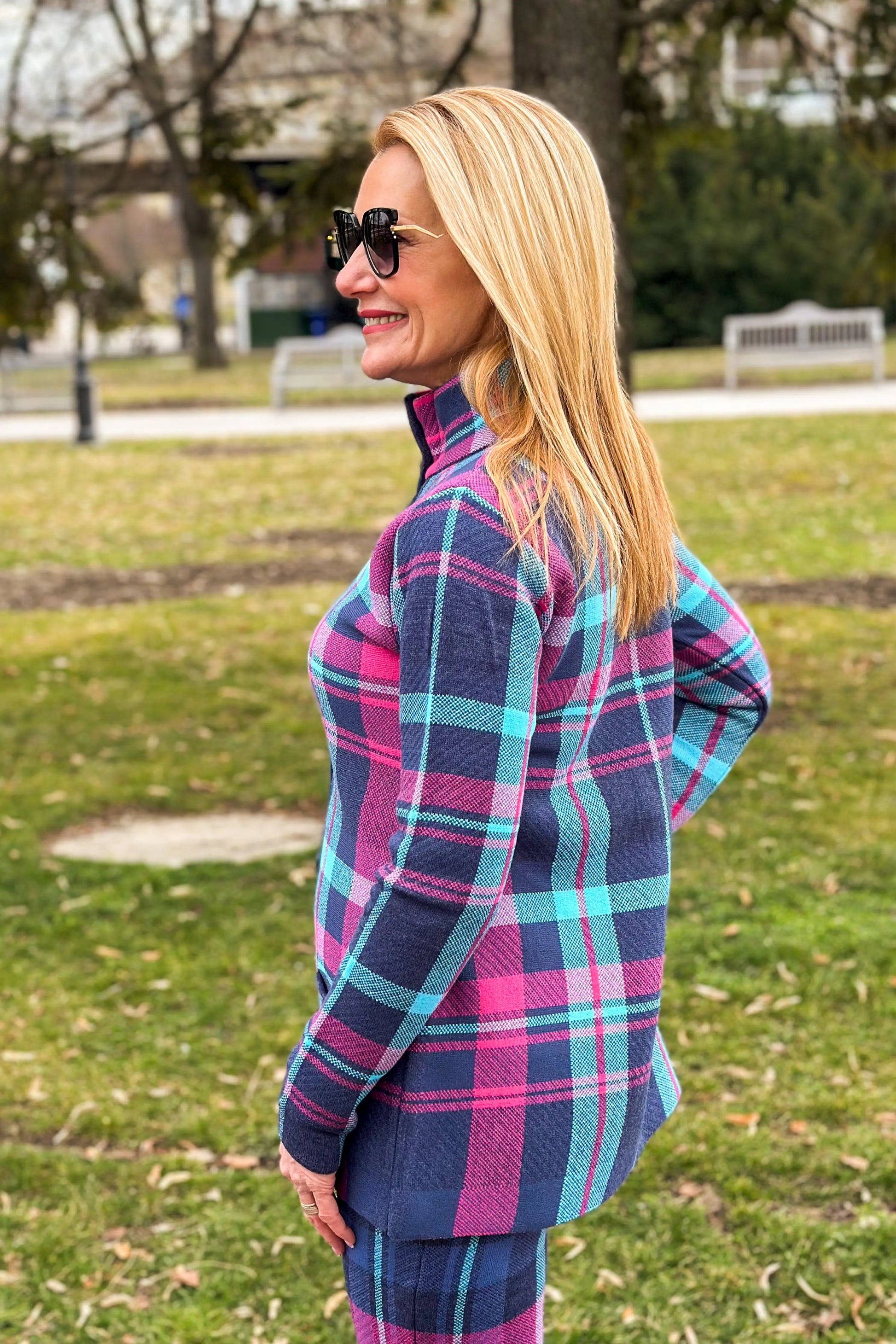 Chic high-neck plaid coat in navy and pink worn with boots.